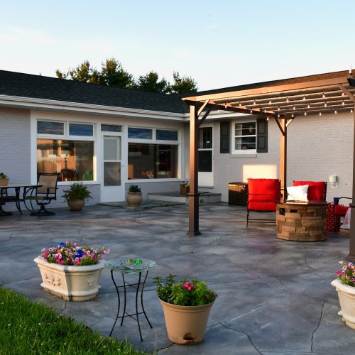 Patio living space with comfortable seating around fire pit under pergola with dining table